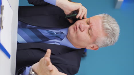Vertical-video-of-Stressed-talking-businessman-on-the-phone.